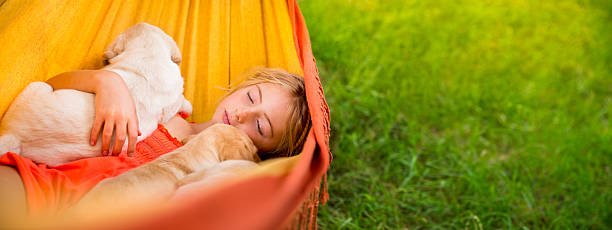 Girl sleeping with two labrador puppies in hammock