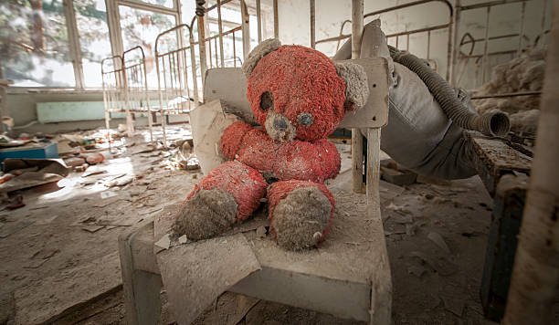 Chernobyl - Teddy bear in abandoned kindergarten Old red teddy bear sitting on a chair in an abandoned kindergarten in Pripyat - Chernobyl nuclear power plant zone of alienation chornobyl photos stock pictures, royalty-free photos & images