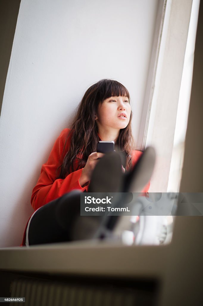 Young Woman Sitting in Gallery Window With Smart Phone Young woman in Berlin sitting on window sill in a gallery with her smart phone and daydreaming. 20-29 Years Stock Photo Young Woman Sitting in Gallery Window With Smart Phone Young woman in Berlin sitting on window sill in a gallery with her smart phone and daydreaming. 20-29 Years Stock Photo