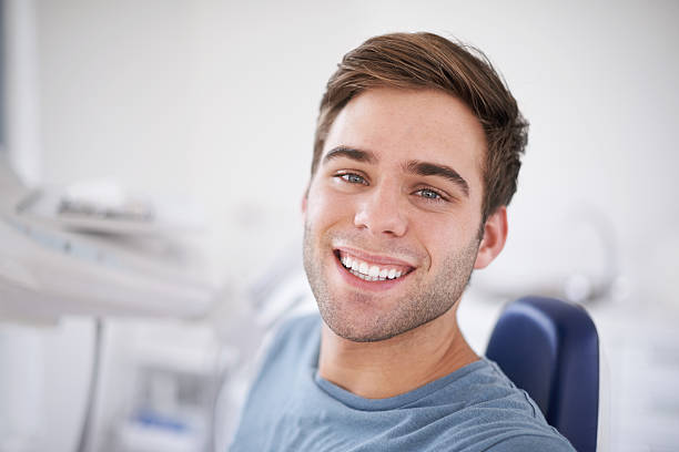 Ready for this! Portrait of a young, smiling man sitting in a dentist&#039;s chairhttp://195.154.178.81/DATA/shoots/ic_783161.jpg dentists chair stock pictures, royalty-free photos & images