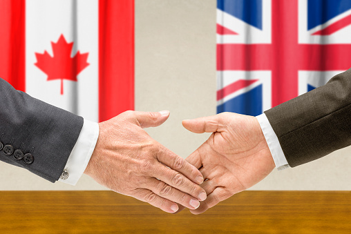 Representatives of Canada and the UK shake hands