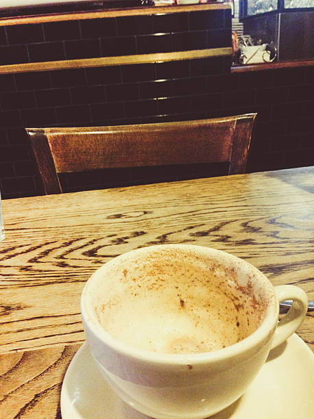 Empty coffee cup facing empty chair in a cafe