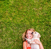 istock Girl with puppy lying on grass 482662389