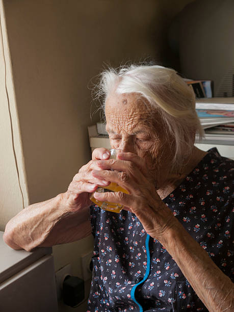 Thirsty old lady drinking stock photo