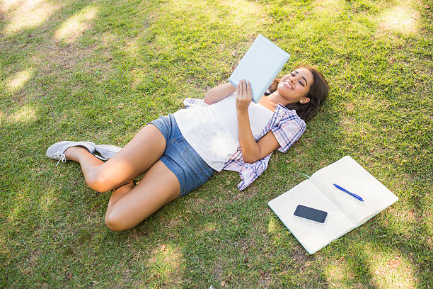 istock Pretty brunette relaxing in the grass and reading book 482670692