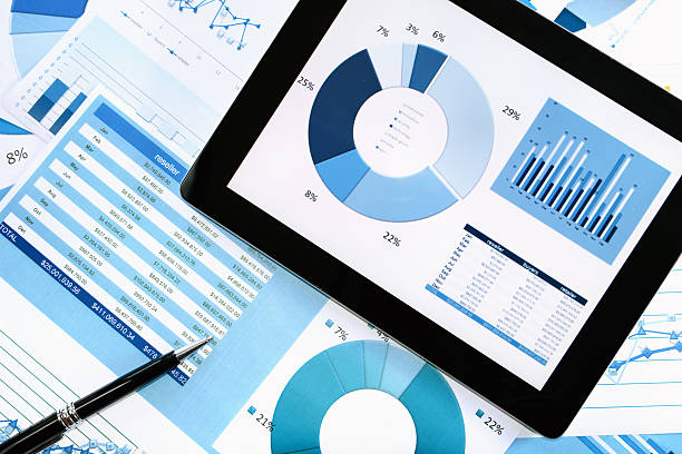 istock Pen and computer tablet on pile of finance charts 482670881