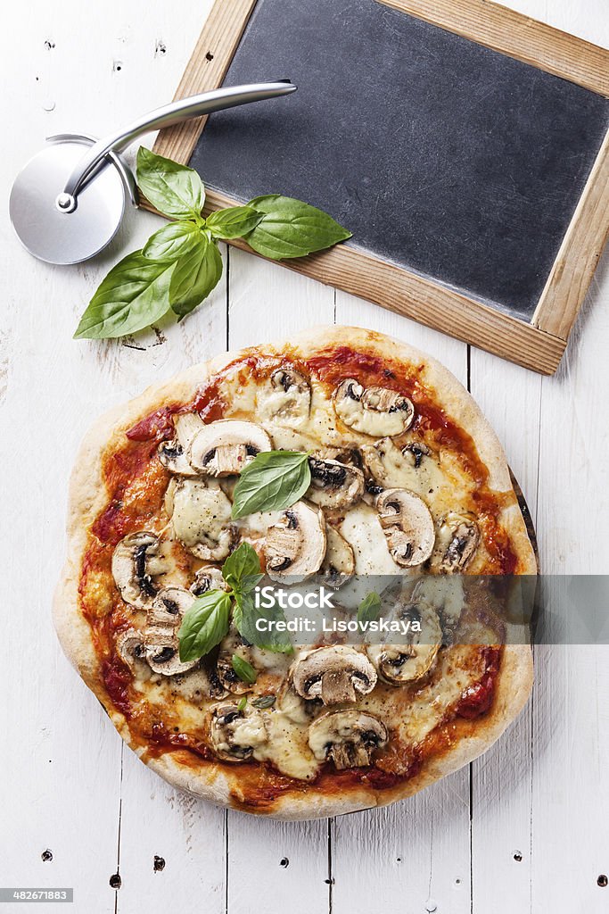 Pizza with mushrooms Pizza with mushrooms and basil on wooden table Edible Mushroom Stock Photo