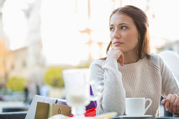istock Young woman looking away while sitting at sidewalk cafe 482674643