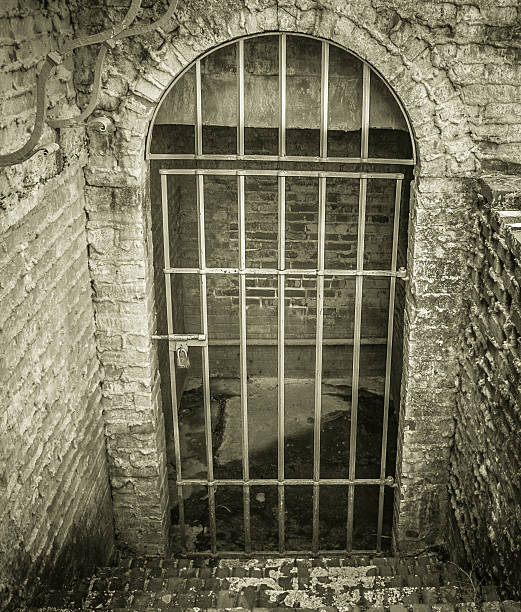 Stone stairs lead to a locked dungeon style cell with a dirty cement floor.