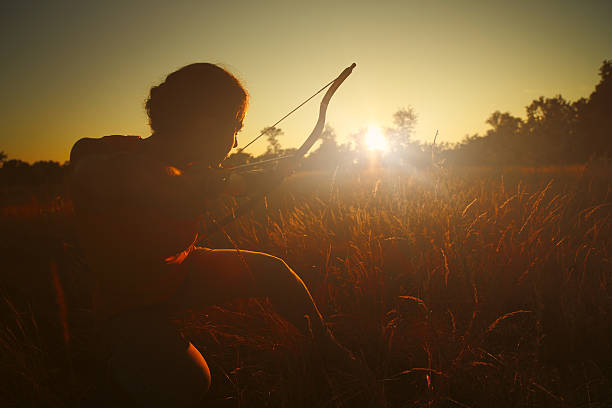 Female archer in the field at sunset