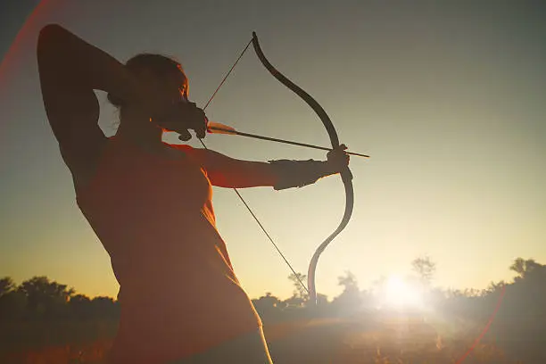 Female archer in the field at sunset