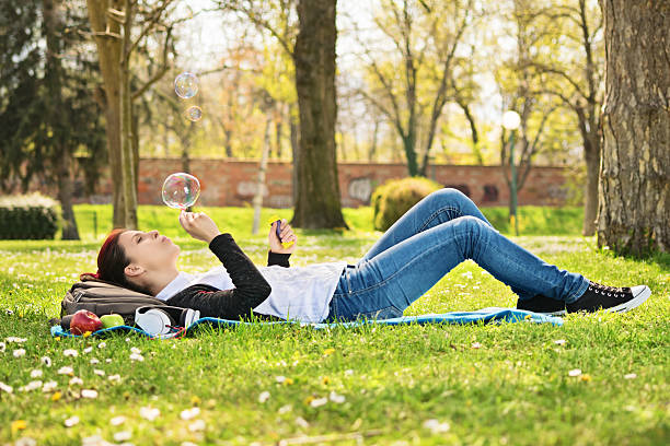 istock Young girl daydreaming on a meadow and blowing soap bubbles 482688616