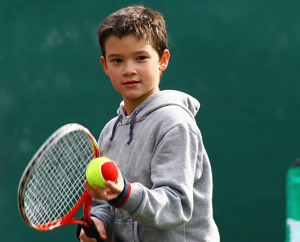 pequeno jogador de ténis em um verde turva de fundo - tennis teenager little boys playing imagens e fotografias de stock