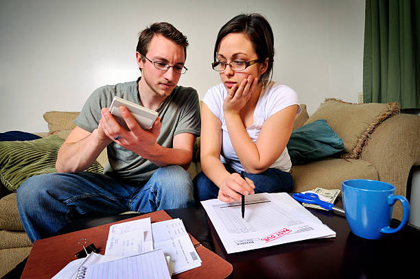 Young Couple Dealing with Their Finances Young apartment-dwelling couple working on household budgetary matters, complete with a "past due" invoice and some tough choices.  mike cherim stock pictures, royalty-free photos & images