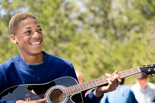 música: joven adolescente tocando la guitarra de ascendencia africana.  al aire libre, parque. - sunny cantante fotografías e imágenes de stock