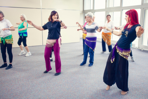 Instructor teaching group of senior women belly dance in a dance studio.