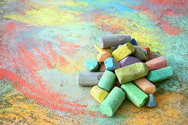 Pile of Sidewalk Chalk a collection of colorful sidewalk chalk is piled up on a rainbow drawing, outside on the pavement. chalk stock pictures, royalty-free photos & images