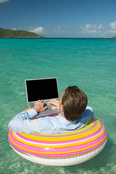 istock Relaxed Businessman Typing on Laptop Floating in Tropical Bay 482692199