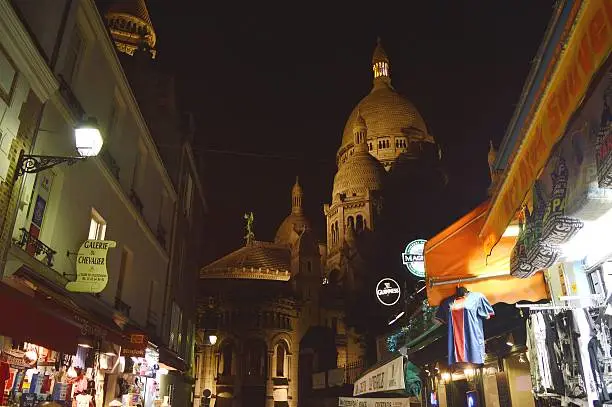 Walking through Montmartre district at night with Sacre Coeur glowing in the distance