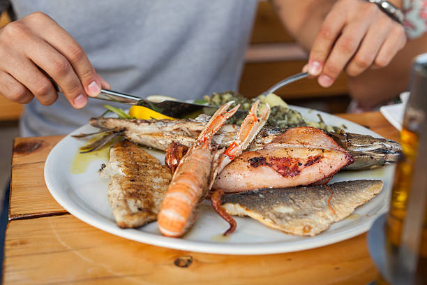 istock Young men sitting behind the table and eating seafod. 482698054