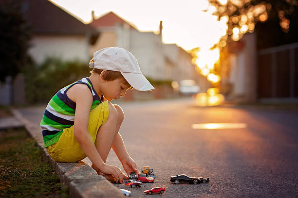 lindo menino, brincando com carros de brinquedo na rua little - calming down - fotografias e filmes do acervo