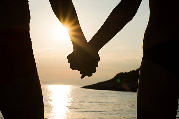 istock Couple on a beach holding hands at sunset 482706658