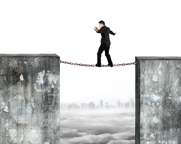 istock Businessman balancing rusty chain connected concrete walls 482707452