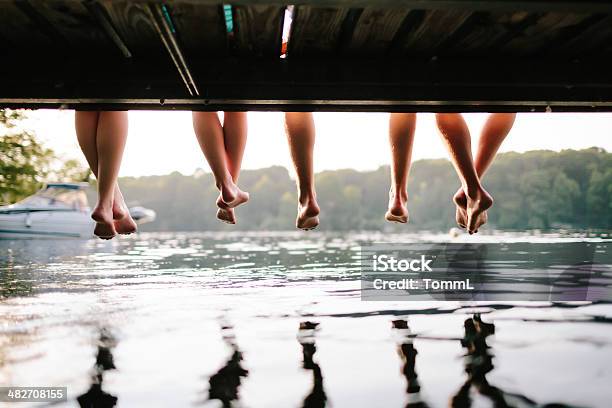 Two Couples Sitting On A Jetty Stock Photo - Download Image Now - Summer, Lake, Beach