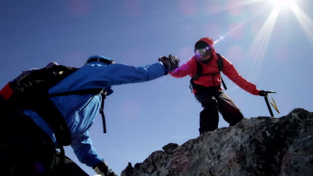 Climbers are helping each other over rocks on mountain