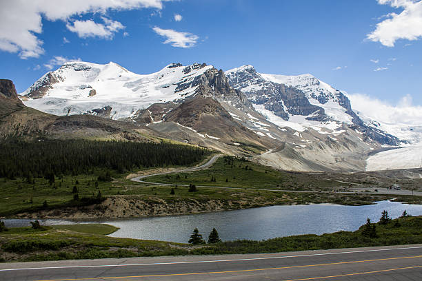 istock Mountain road with forest and snowy peaks 482714994