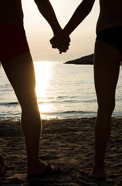 istock Couple on a beach holding hands at sunset 482720444