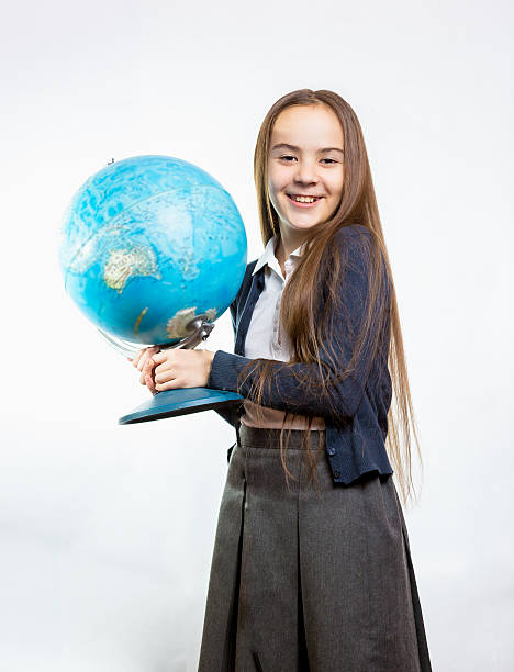 istock happy schoolgirl posing with globe against white background 482730866