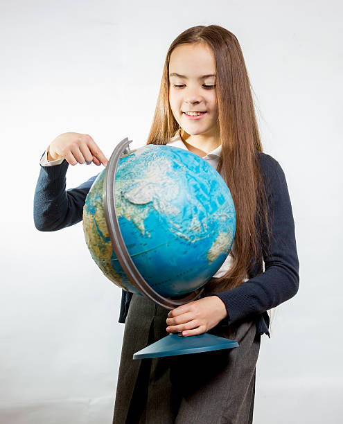 istock cute smiling girl pointing at Earth globe against white backgrou 482730870
