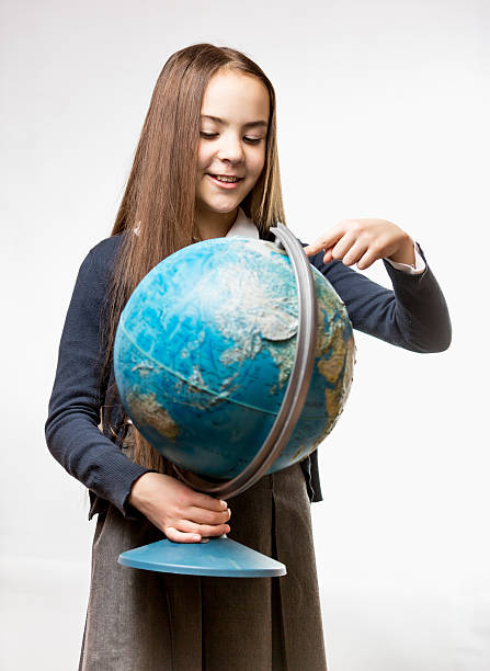 istock smiling girl in school uniform pointing at Earth globe 482730872