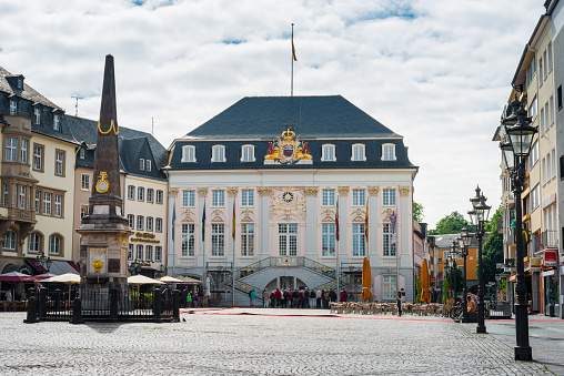Bonn, Germany - June 21, 2015: market square in Bonn / Germany with the old town hall in background and an obelisk on left side. Many restaurants are located around this place. Some tourists are standing in front of the old town hall