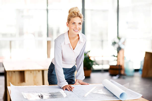 istock Contractor With Blueprint At Desk Looking Away In Office 482737404