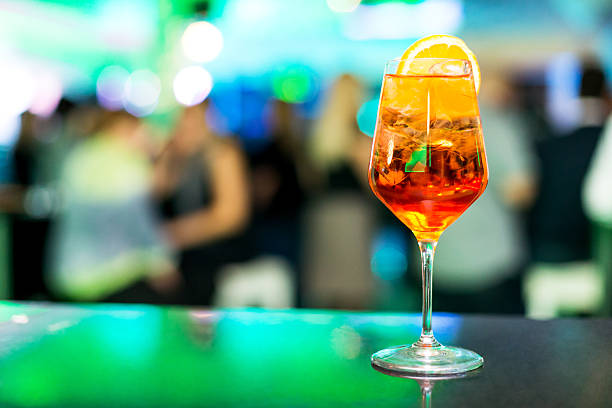 Spritz cocktail Cocktail Spritz garnished with slice of orange, people in background, copy space fruit garnish stock pictures, royalty-free photos & images