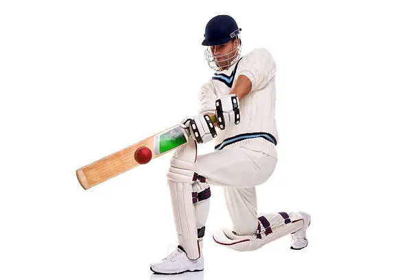 Cricketer down on his knee playing a shot, studio shot on white background.
