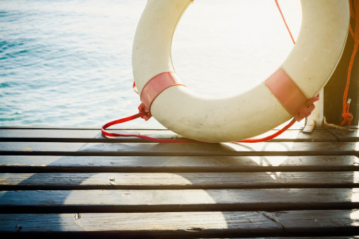 Safety Element - Life Preserver on wood floor, sea as background