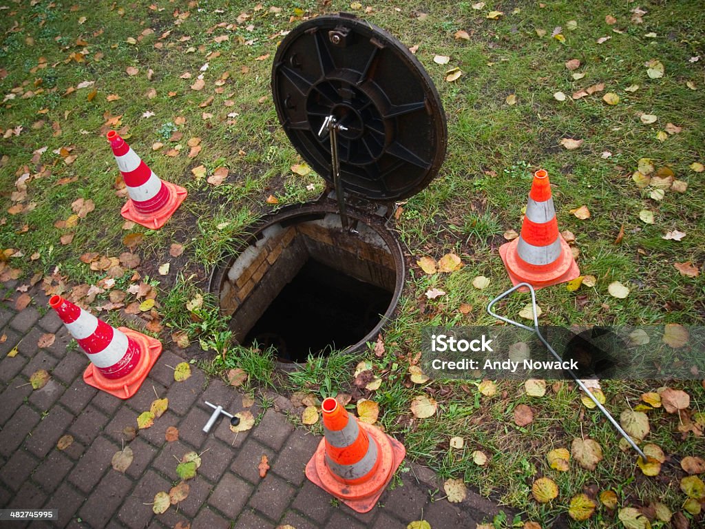 open manhole on the lawn enhanced wide-angle view of open and closed with pylons Mannlochs on a lawn at the wayside Sewer Stock Photo