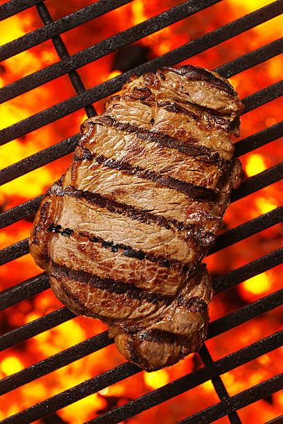Grilled Steak Steak sizzling on a grill. steak vertical beef meat stock pictures, royalty-free photos & images