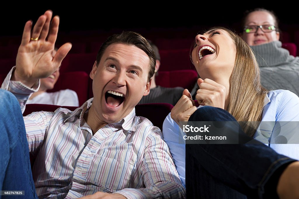 Couple and other people in cinema Couple and other people, probably friends, in cinema watching a movie, it seems to be a funny movie Laughing Stock Photo