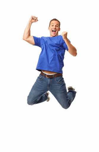 Full length of an exhilarated young man in casual wear jumping in mid-air. Vertical shot. Isolated on white.