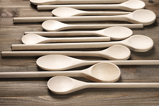 Assorted wood spoons in row on rustic wooden background. Shallow DOF, focus on foreground.