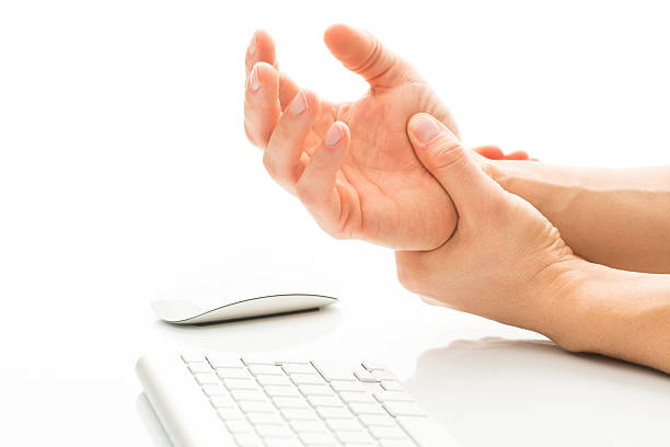 Illustration of Carpal tunnel syndrome Working too much - suffering from a Carpal tunnel syndrome - young man holding his wrist in pain due to prolonged use of keyboard and mouse over white background (color toned image; shallow DOF) carpal tunnel syndrome photos stock pictures, royalty-free photos & images