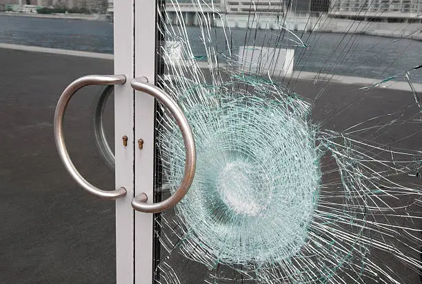 Photo of Broken window on business glass door shattered by vandalism