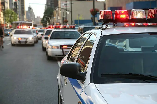 Row of police cars with flashing lights and sirens on the streets of Manahttan, New York City, New York, USA.