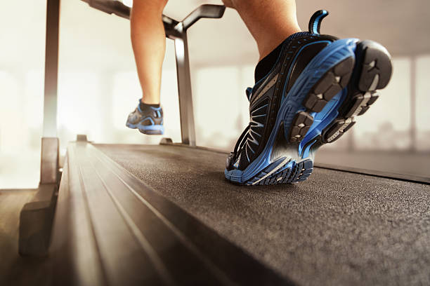 Running on treadmill Man running in a gym on a treadmill concept for exercising, fitness and healthy lifestyle treadmill stock pictures, royalty-free photos & images