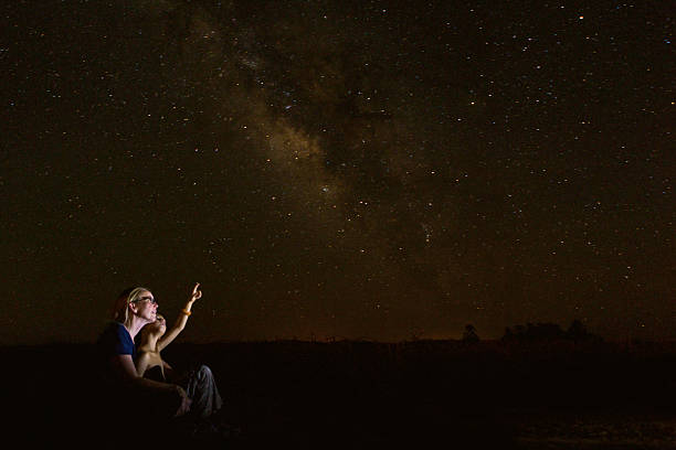 Mother star gazing with young son while he studies constellations