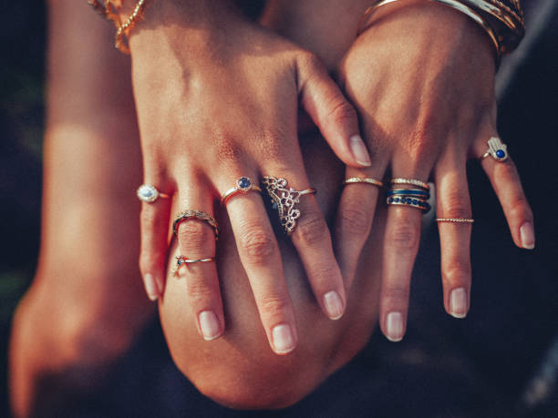 Boho girl's hands looking feminine with many rings Cropped closeup of a boho girl's hands with many rings on her fingers, in gold and silver with dark blue stones ring jewelry stock pictures, royalty-free photos & images